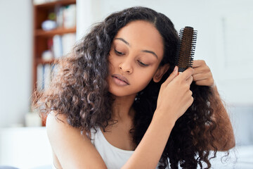 Brushing hair, woman and morning routine at home with care and grooming. Bathroom, relax female person and curly hairstyle knots holding a brush in a house with haircare, natural beauty and youth