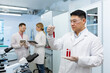 © Liubomir - Serious asian scientist inside laboratory researching blood in test tubes, man in medical white coat.