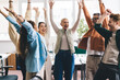 © BullRun - Group of diverse friends standing in office and raising arms