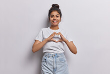 Good Looking Indian Woman Radiates Love Her Hands Forming Heartfelt Gesture Reminding Us Of Power Of Love And Compassion Smiles Broadly Dressed In Casual T Shirt And Jeans Isolatd On White Background