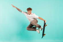 Young Crazy Guy Rides Skateboard And Jumps On Blue Isolated Background, Hipster In Sunglasses Flies
