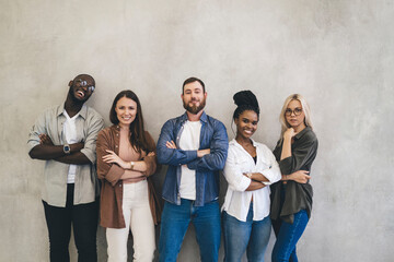 Group of diverse people standing near gray wall