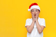 © Богдан Маліцький - shocked little asian boy in santa hat is surprised and looks away on yellow isolated background