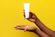 © Богдан Маліцький - hands of african american man hold white empty tube of cream on yellow isolated background, hands squeeze out