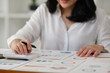 © saltdium - Close up image of businesswoman hand counting a numbers while Analyze graphs, diagrams and figures of financial document on office desk.