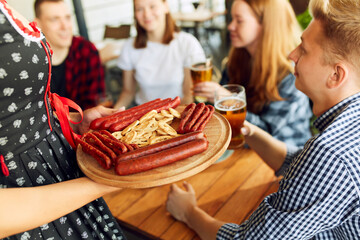 Wall Mural - Waitress serving plate with many tasty sausages and pretzels. Appetizers for beer. Friends meeting. Concept of oktoberfest, traditional taste, friendship, leisure time, enjoyment