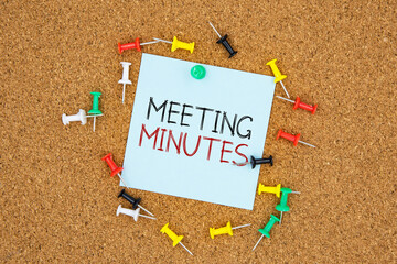 Poster - Meeting minutes text on light blue post-it paper pinned on bulletin cork board surrounding by multi color pins. This message can be used in business concept about meeting minutes.