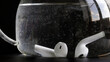 White wireless tws earbud underwater in a glass bowl. The concept of testing the waterproofness and water resistance of wireless headphones. Black background. Photo. Selective focus.