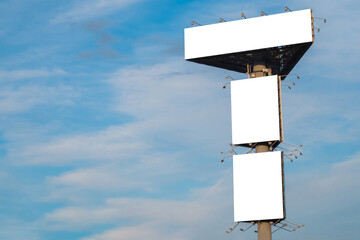 Wall Mural - mock up image: three blank white billboards or large displays on tower against blue sky with clouds.