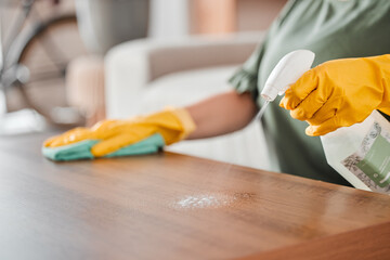 Wall Mural - Hands, cleaning and spray on a wooden table for hygiene, disinfection or to sanitize a surface in a home. Gloves, bacteria and product with a woman cleaner in the living room for housework or chores