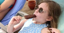 Little And Cute Girl Eating Chocolate Ice Cream On Beach On Vacation. Cold Delicious Ice Cream On Hot Day