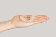 Closeup of woman hand showing invisible orthodontics cosmetic aligners. Indoor studio shot isolated on gray background.
