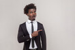 © khosrork - Portrait of surprised amazed man with petit goatee pointing away on blank copy space, showing logo or amazing offer, wearing white shirt and tuxedo. Indoor studio shot isolated on gray background.