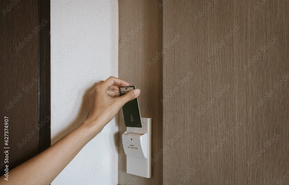 Female hand insert key card in holder on hotel room wall for opening ...