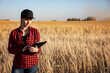 © Designpics - Portrait of a young farm woman standing in a mixed crop field of barley and oats at harvest time, using sophisticated agricultural software technologies on a pad; Alcomdale, Alberta, Canada