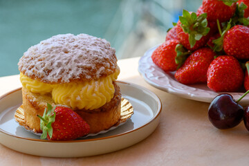 Tarte tropezienne or La Tarte de Saint-Tropez - dessert pastry consisting of filled brioche with cream and fresh berries served outdoor with fresh ripe strawberry