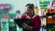 © Marco - Stressed female entrepreneur owner of small business struggling with hard times holding tablet and staring at the bottom line of the grocery store