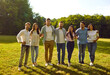 © Studio Romantic - Happy friends having fun in the park in the summer. Group of young people huddling on a green grass lawn. Several men and women standing backlit on green grass