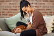 © CineLens/peopleimages.com - Love, woman with her cat and on a sofa in living room of her home sitting. Animal care or support, quality or bonding time and happy female person pet her kitten on a couch together at her house