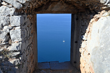 Sticker - View of the sea and sailboat through an old stone window on the Palamidi fortress Nafplio