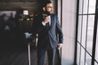 © BullRun - Confident businessman standing at window and looking away