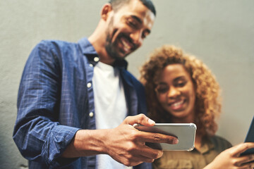 Aufkleber - We love sharing our selfies on social media. Shot of a young couple looking at a smartphone together outside.