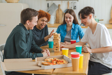 Wall Mural - Home party. Friends spending time together playing in board game crash wooden tower at home. Happy diverse group having fun together indoor. Mixed race young buddies best friends enjoying weekend