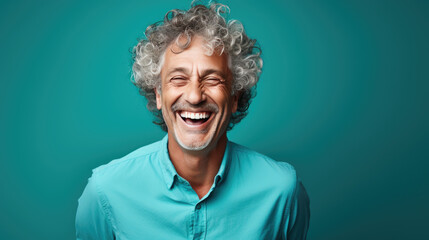 middle-aged man laughs against a blue background.