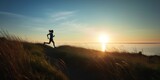 Fototapeta Kosmos - Energetic Silhouette of a Woman Running on Meadow Hill at Sunset, Enjoying the Coastal Beauty of Blue Sky, Ocean, and Shoreline in a Scenic Panoramic View, Embracing an Active and Healthy Lifestyle