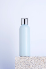 Wall Mural - Blue cosmetic facial cleanser bottle on natural stone podium, closeup