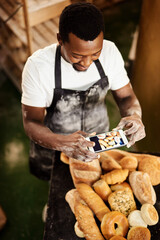Poster - This picture is for todays online baking tips. Cropped shot of a male baker taking a picture on his cellphone of a selection of freshly baked bread.