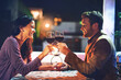 © Adene Sanchez/peopleimages.com - Cheers, wine and couple on date in restaurant, romance and happiness in celebration of love and drinks. Romantic honeymoon night, man and woman toast glasses in cafe, smile on dinner holiday travel.