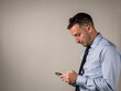 © Javier - Hombre elegante mirando su celular con mala postura en su espalda