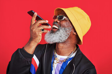 Poster - Sending voice messages to make everyones day. Studio shot of a mature man holding his cellphone against a red background.