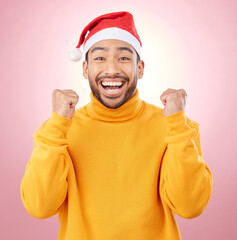 Wall Mural - Portrait, excited and smile, man with Christmas hat for fun and yes at festive holiday on pink background. Happy, winning celebration and model with santa cap and winter vacation success in studio.