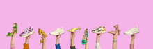 Multiple People's Hands Holding Shoes Of Different Colors And Styles On Isolated Pink Background With Copy Space. Creative Advertising Banner. Shoe Summer Sale, Discount Concept. Barbie Pink Style