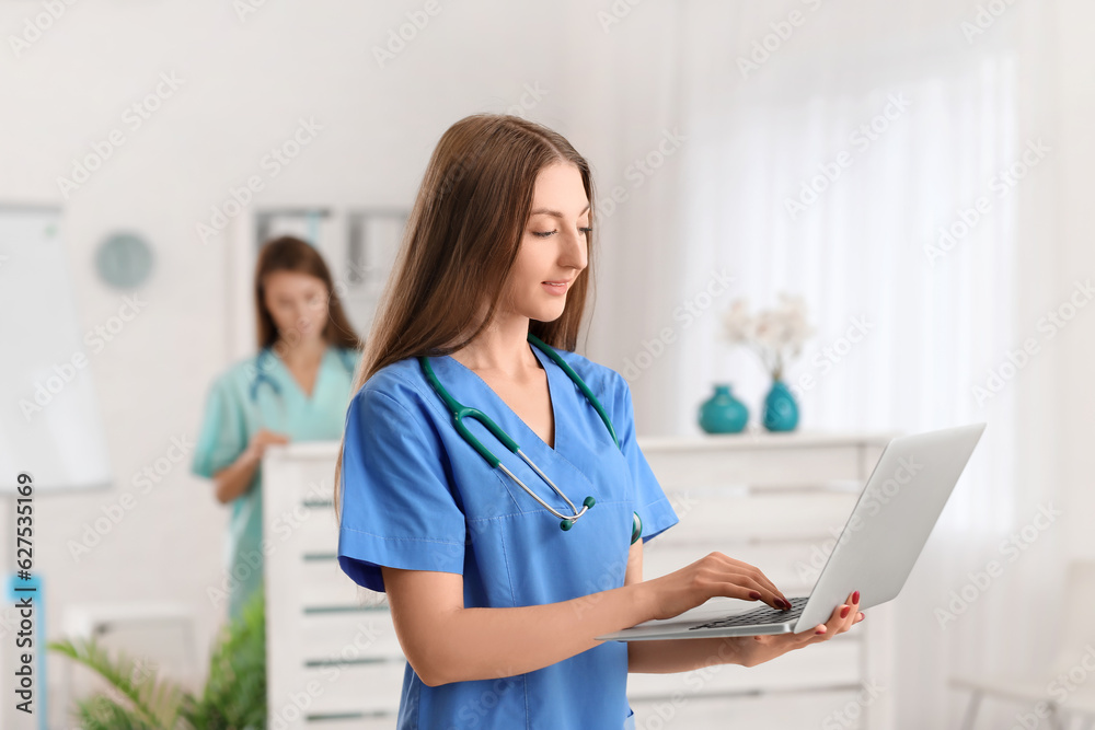 Female medical assistant using laptop in clinic