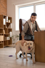 Canvas Print - Young man with cute Labrador dog in office