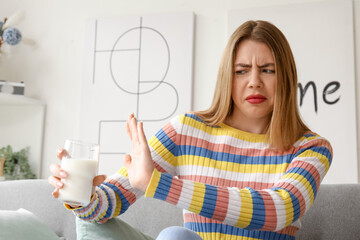 Poster - Displeased young woman with glass of milk at home