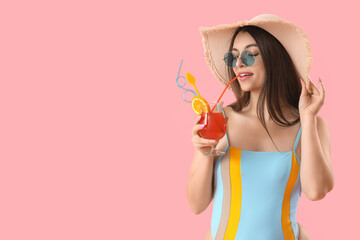 Poster - Young woman drinking summer cocktail on pink background