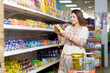 © Niks Ads - Indian woman looking product detail while purchasing at grocery shop.