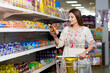 © Niks Ads - Indian woman looking product detail while purchasing at grocery shop.