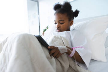 Wall Mural - African american girl patient lying on bed using tablet in patient room at hospital