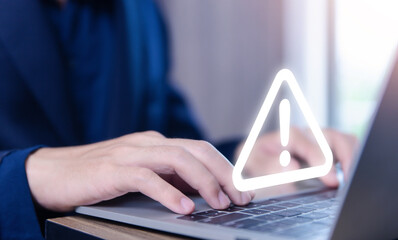 Wall Mural - businessman using laptop showing warning triangle and exclamation sign icon warning of dangerous pro