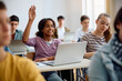© Drazen - Happy black high school student raising her arm during computer class in classroom.