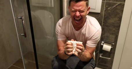 Adult man with pain on toilet seat. Bowel problem and constipation concept