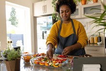 Happy plus size african american woman in apron preparing meal in kitchen