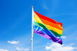 LGBT pride rainbow flag blowing in wind in front of blue sky
