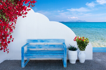 the colors of Greece with a bench in front of a wall and a view to the beautiful mediterranean sea