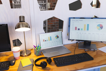 Computer and laptop on desk in casual office
